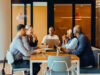 Fünf Personen sitzen an einem Meeting-Tisch